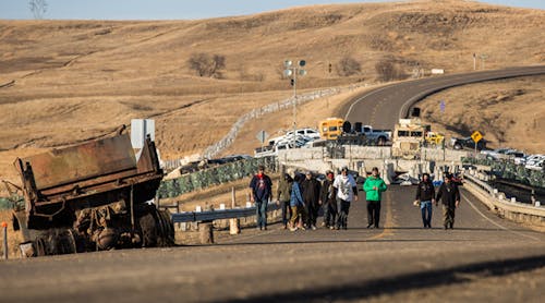 Standing Rock, North Dakota, November 26, 2016. Water protectors return from the Highway 1806 blockade north of the Oceti Sakowin Camp at Standing Rock as police look on from behind the concrete barriers. FrostOnFlower/iStock